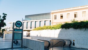 A modern building with a glass facade, a signpost with a map, and an escalator. - Acropolis Lux 2 Bedroom Apt,CBD, H/TUB, fast Wifi-1min from Museum&Metro station (Athens)