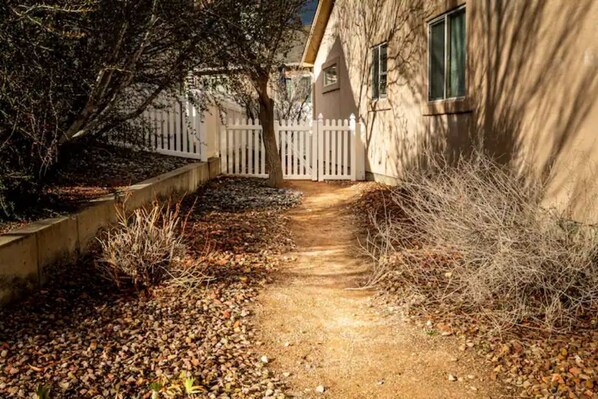 Pathway leads to a single-story building with a white picket fence.