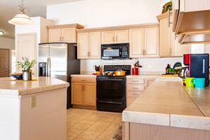 Enjoy cooking in this well-equipped kitchen with a large island, sink, and stainless steel appliances.
