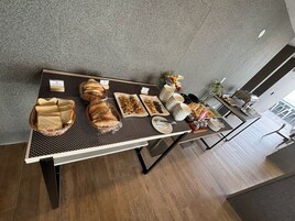 Una mesa de desayuno buffet con diversos panes, pasteles y salsas.