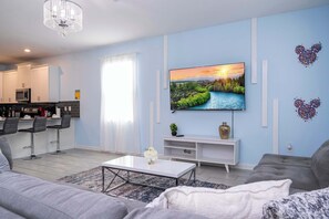 Una sala de estar moderna con televisor de pantalla plana, sofá gris y una mesita de centro.