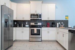 Una cocina moderna con armarios blancos, electrodomésticos de acero inoxidable y salpicadero de azulejos.