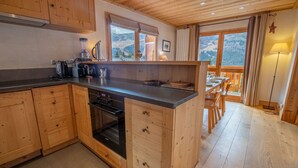A kitchen with wooden cabinets, a built-in oven, and a dining area with a table and chairs.