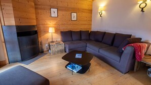 A cozy living room with a wooden ceiling, a sofa, a coffee table, a lamp, and a fireplace.