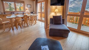 A wooden interior with a dining area, a sofa, and a TV.