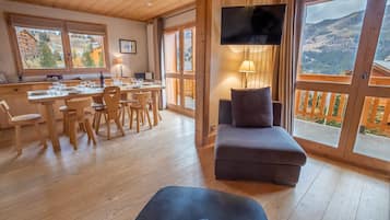 A wooden interior with a dining area, a sofa, and a TV.