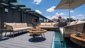 A rooftop terrace with outdoor seating, a glass table, and a view of a historic building with a red dome. - Hotel Patio Santiago (Querétaro)