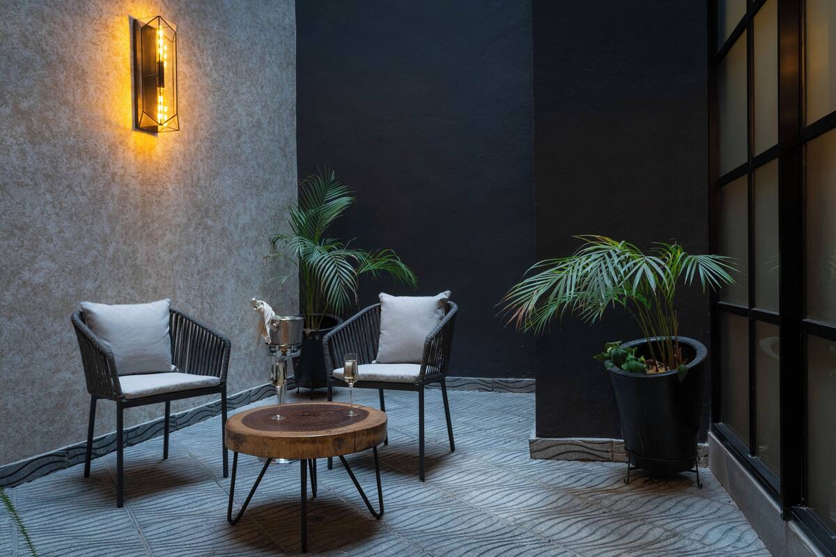 A modern outdoor seating area with two wicker chairs, a wooden table, and a potted plant.