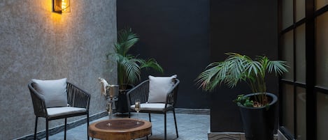 Un espacio al aire libre moderno con dos sillas de mimbre, una mesa de madera y una planta en maceta.