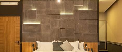 Um quarto moderno com uma cama grande, cabeceira de madeira e luminária no teto.