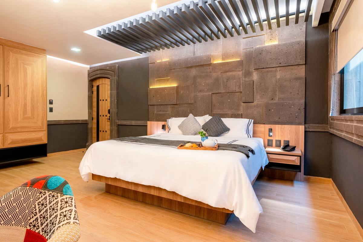 A modern bedroom with a large bed, wooden headboard, and a built-in nightstand.