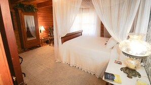 Une chambre à coucher avec un lit à baldaquin, une table de chevet avec une lampe et une petite table de nuit avec un livre et un verre.