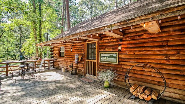 Un chalet rustique doté d’une terrasse en bois, d’un porche abrité et d’une cheminée.