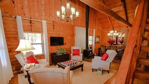 L’intérieur d’un chalet confortable, avec une cheminée, des murs en bois et un lustre.