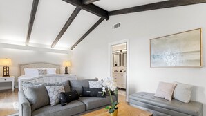 A modern bedroom with a large bed, two sofas, a wooden coffee table, and a painting on the wall. - San Marcos Farm Stay — Mini Cows, Hot Tub & Games — Sleeps 12 (San Marcos)