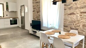 A modern kitchen with white cabinets, a built-in oven, and a stone accent wall. - The Backyard (Eva)