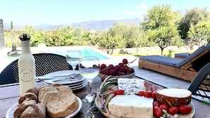 A table set with food and drinks, overlooking a pool and mountains. - The Backyard (Eva)