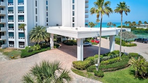 A modern hotel with a covered entrance, palm trees, and a view of the ocean. - Gorgeous Beachside Condo in superior Longboat Location (Longboat Key)
