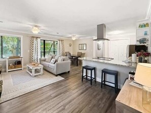 A modern living room with a sofa, coffee table, and a dining area with chairs.