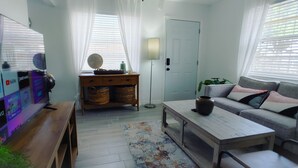 Una sala de estar con televisor, sofá, mesa de centro y una puerta.