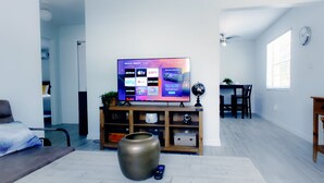 Una sala de estar con un televisor de pantalla plana, un sofá, una mesa de centro y un jarr ón decorativo.