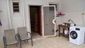 A laundry area with a washing machine, two chairs, a wooden table, and a door leading to another room. - Aito 2 in Muri (Muri)