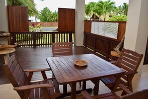 A wooden deck with a table and chairs, surrounded by a wooden fence and a white lattice panel.