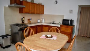 A kitchen with wooden cabinets, a stove, a sink, and a dining table with chairs. - Aito 2 in Muri (Muri)