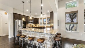 Una cocina moderna con una isla grande, electrodomésticos de acero inoxidable y taburetes de bar.