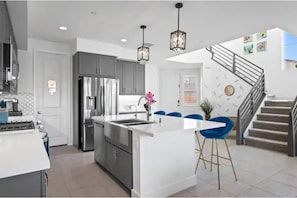 Enjoy cooking in this well-equipped kitchen with a central island, stainless steel appliances, and pendant lighting.