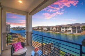 Enjoy a serene river view from this balcony with a wicker chair and table.