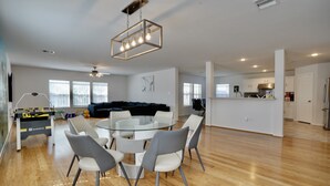A spacious living area with a round glass table and chairs, a black sectional sofa, and a kitchen in the background. - Houston Wall Mural,  A Getaway Escape  (Houston)
