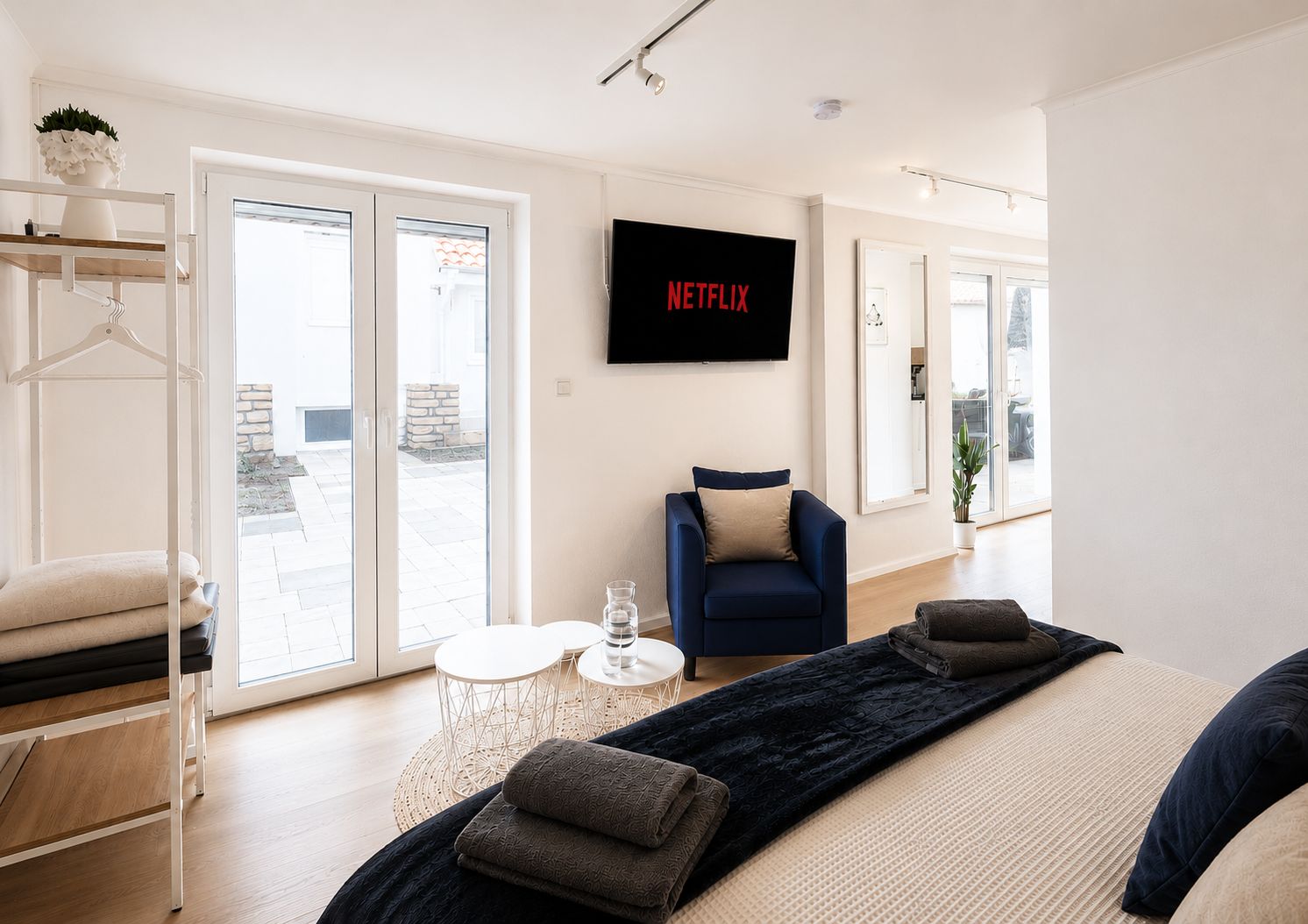 A modern living room with a sofa, a coffee table, and a TV mounted on the wall displaying 'NETFLIX'.