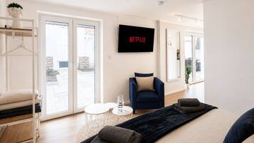 A modern living room with a sofa, a coffee table, and a TV mounted on the wall displaying 'NETFLIX'.