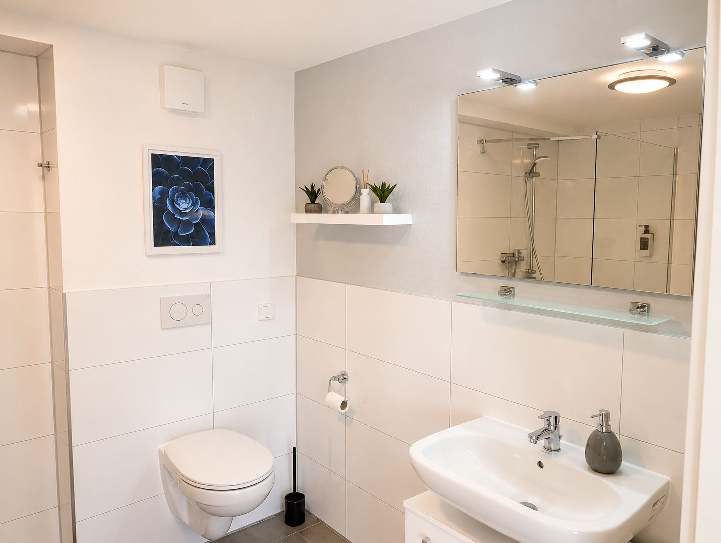 Ein modernes Badezimmer mit Toilette, Waschbecken, Spiegel und Dusche.