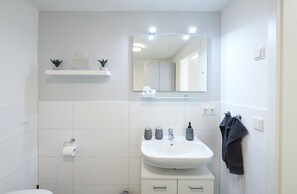 A modern bathroom with a white sink, mirror, and two towel racks.