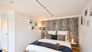 A modern bedroom with a bed, bedside tables, and a patterned wallpaper. - Stylish apartment: quiet, 24/7 self check-in & Wi-Fi, street parking (Göttingen)