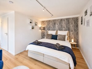 Un dormitorio moderno con cama, mesitas de noche y un papel tapiz estampado.
