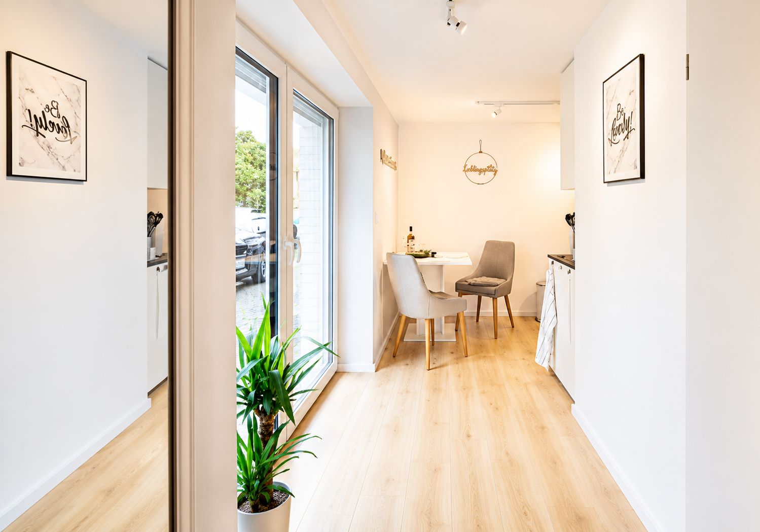 Una cucina moderna con zona pranzo, una pianta in vaso e vista sulla strada.