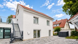 A two-story residential building with a red-tiled roof, a staircase leading to the entrance, and a paved driveway. - Stylish apartment: quiet, 24/7 self check-in & Wi-Fi, street parking (Göttingen)