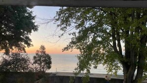 A view of a body of water during sunset, with trees and a concrete structure in the foreground. - Peaceful Lakefront Living – 3-BR Home with Breathtaking Views; Pet & Smoke-Free (Charter Township of Berlin)