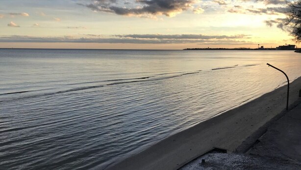 A beach with a concrete walkway along the water. - Peaceful Lakefront Living – 3-BR Home with Breathtaking Views; Pet & Smoke-Free (Charter Township of Berlin)