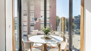 A round table with chairs in a room with large windows. - ALTIDO Apartamento luminoso na zona sossegada do Porto, perto do Mercado Bom Suc (Porto)