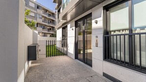 A modern building with a paved entrance, glass doors, and a metal fence. - ALTIDO Apartamento luminoso na zona sossegada do Porto, perto do Mercado Bom Suc (Porto)