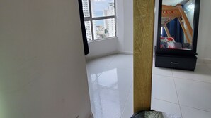 Ein Zimmer mit großem Fenster, einem Bett, einem Holzkopfende und einem Spiegel.