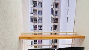 Ein Balkon mit zwei schwarzen Barhocker und einer Holzbank.
