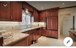 Kitchen features an oven, refrigerator, and sink with a window above.