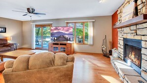 Ein Wohnzimmer mit Kamin aus Stein, einem Fernseher und einem Sofa.