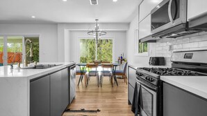 Una cocina moderna con una isla central, electrodomésticos de acero inoxidable y un comedor con candelabro.