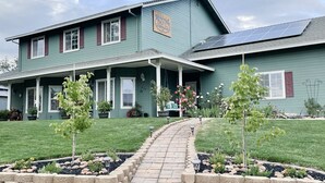 Ein zweigeschossiges Haus mit überdachter Veranda, Solaranlage und einem gepflegten Garten.